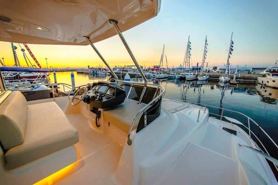 Luxury yacht deck with modern controls and seating, overlooking a marina at sunset. Perfect for sail.